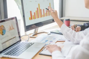 Team bei der Arbeit mit Diagrammen und Statistiken auf einem Computerbildschirm. Analyse und Optimierung von Bauprojekten durch präzise Datenbewertung.